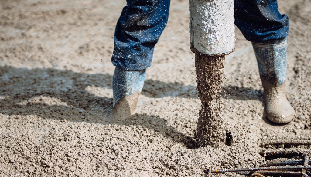 Close-up of concrete placement over steel reinforcement during commercial construction, highlighting high-performance concrete, cement innovation, and low-carbon infrastructure materials.